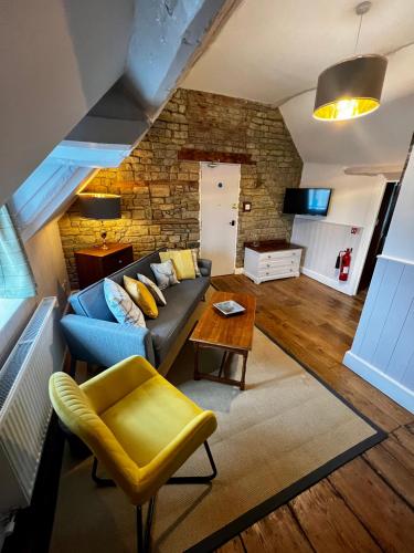 a living room with a blue couch and a stone wall at The Lion, Tredington in Shipston on Stour