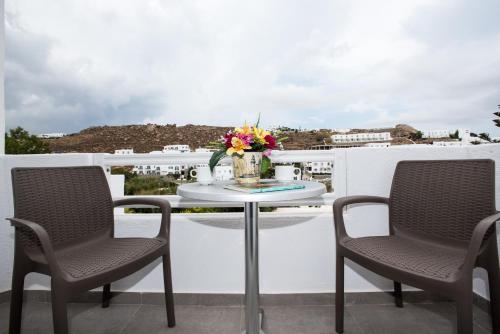 a table on a balcony with chairs and flowers on it at Mina Studios in Platis Yialos Mykonos