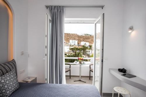 a bedroom with a bed and a balcony with a table at Mina Studios in Platis Yialos Mykonos