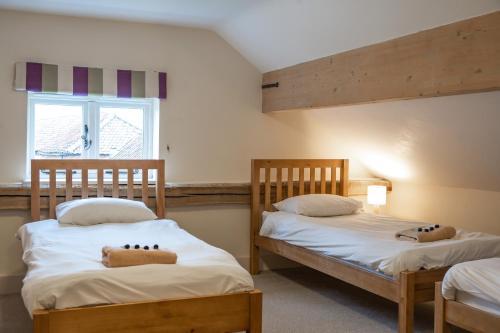 two twin beds in a room with a window at Chestnut Barn, North Norfolk with private hot tub & close to beaches in Norwich