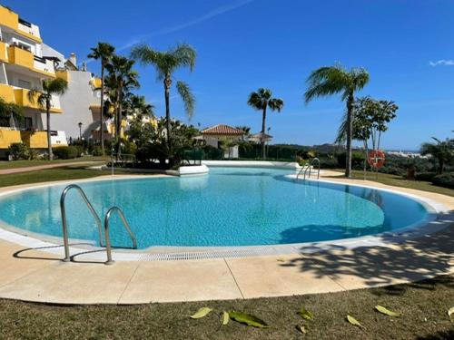 a large swimming pool with palm trees and a building at Mijas,Calanova grand Golf in La Cala de Mijas