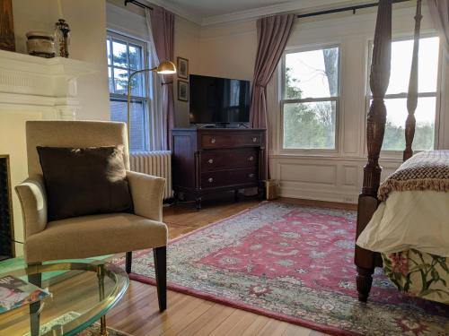 a bedroom with a bed and a chair and a television at Stanton House Inn in Greenwich