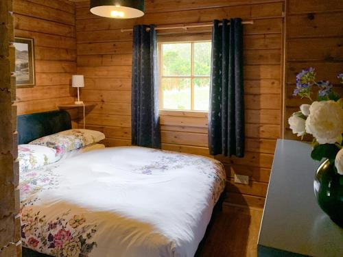 Dormitorio con cama y ventana en una cabaña en Chalet 2, en Torcastle