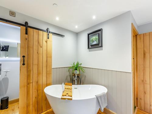 La salle de bains est pourvue d'une baignoire et d'une porte en bois. dans l'établissement The Mill, à Llandegley