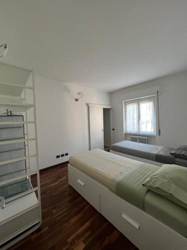 1 dormitorio blanco con 2 camas y ventana en Casa Lella, en Dervio