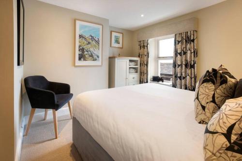 a bedroom with a bed and a chair and a window at The Snug 'Keswick' in Keswick