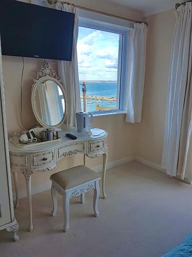 a white dressing table with a mirror and a window at Palma Guest House in St Ives