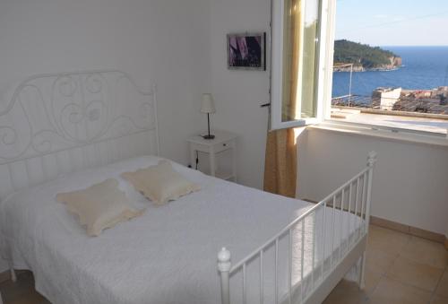 a white bedroom with a bed and a window at Apartment Chic Ploce in Dubrovnik