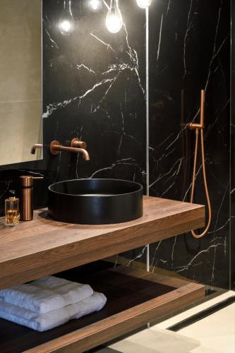 La salle de bains est pourvue d'un lavabo et d'un mur en marbre noir. dans l'établissement Rive Petite Venise Appartement Luxe - Centre Ville Colmar - Clim, Ascenseur & possibilité Parking, à Colmar