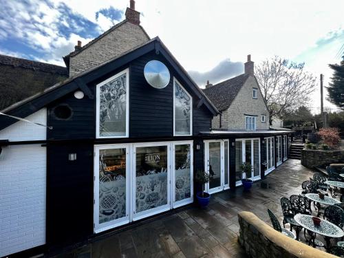 a black building with white windows and tables and chairs at The Lion, Tredington in Shipston on Stour