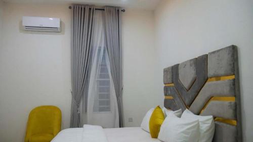 - une chambre avec un lit, une chaise jaune et une fenêtre dans l'établissement Luxury 1 Bedroom & Parlor Service Apartment with beautiful Amenities, à Awoyaya