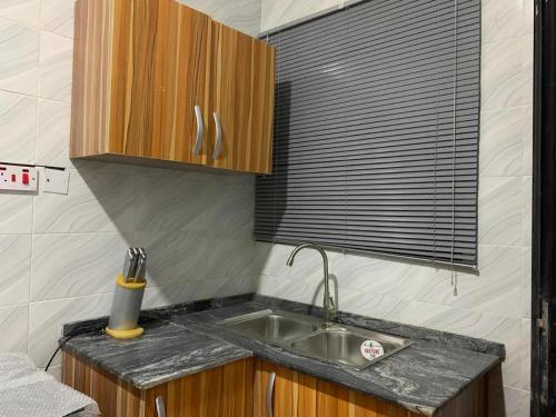 eine kleine Küche mit einem Waschbecken und einem Fenster in der Unterkunft Luxury 1 Bedroom & Parlor Service Apartment with beautiful Amenities in Awoyaya