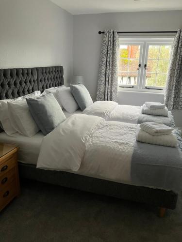 ein Schlafzimmer mit einem großen Bett mit Kissen und einem Fenster in der Unterkunft The Smithy Cottage in Chilham