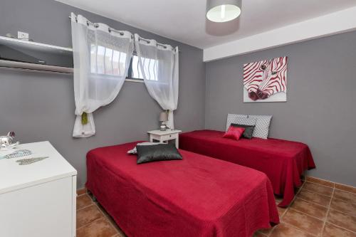 2 camas en una habitación con sábanas rojas en Villa Anabela, en Albufeira