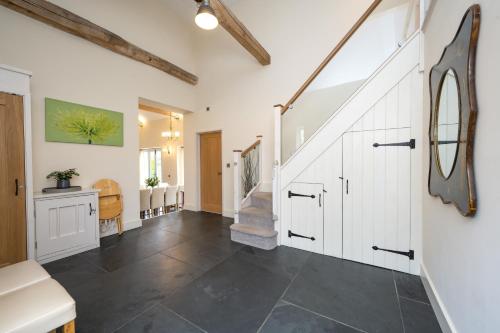 a hallway with white cabinets and black tile floors at Chestnut Barn, North Norfolk with private hot tub & close to beaches in Norwich