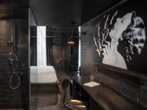 a bathroom with a large picture of a woman on the wall at Hôtel Edgar & Achille in Paris