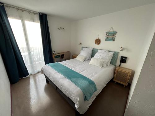 a bedroom with a large bed with white and blue sheets at Logis Hotel De La Clape in Narbonne-Plage