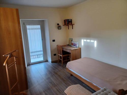 Vezzo的住宿－La corte，一间卧室配有一张床、一张书桌和一个窗户。