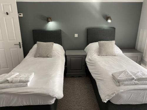 two beds in a room with white sheets and pillows at The Roade House in Northampton