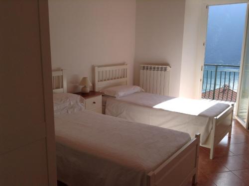 two beds in a room with a balcony at La Casa di Miro in Nesso