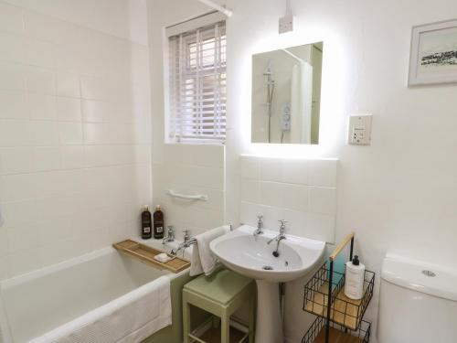 a white bathroom with a sink and a bath tub at Groesffordd in Caernarfon