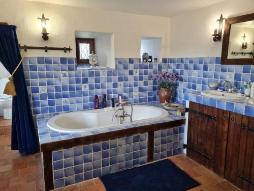 bagno piastrellato blu con vasca e lavandino di Manoir de la Beunèche - location du manoir entier a Roézé-sur-Sarthe