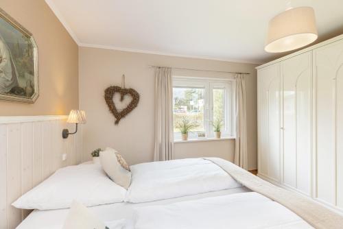 dwa łóżka w sypialni z sercem na ścianie w obiekcie De lüttje Weed unnen w mieście Grömitz