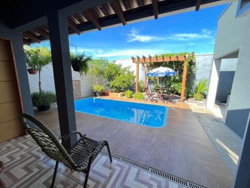 a patio with a pool and two chairs and an umbrella at Aconchego e tranquilidade 1 in Bonito