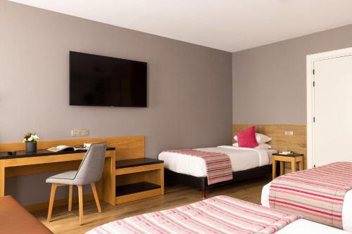 a hotel room with two beds and a desk and a television at Hotel Bristol in Mulhouse