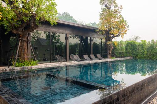 a pool at a resort with chairs and trees at The View Chiang Dao in Chiang Dao