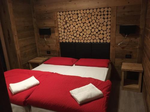 1 dormitorio con 1 cama con sábanas y almohadas rojas en Appartamenti Miriam, en Passo del Tonale