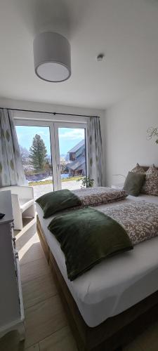 - une chambre avec un grand lit et une grande fenêtre dans l'établissement Ferienwohnungen Bergpanorama, à Bad Mitterndorf
