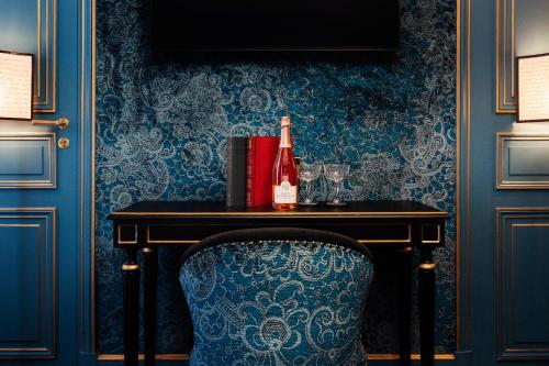 a table with a bottle of wine and a chair at Maison Proust, Hotel & Spa La Mer in Paris