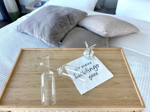 a wooden tray with a glass bottle on a bed at Helles Apartment über den Dächern Rostocks in Rostock