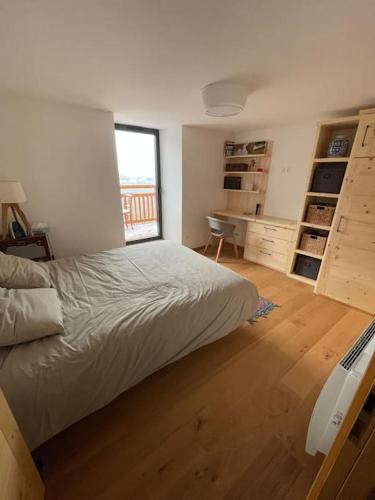 une chambre avec un lit, un bureau et une fenêtre dans l'établissement Le Sarana : 75m2, calme, belle vue avec terrasse., à Les Deux Alpes