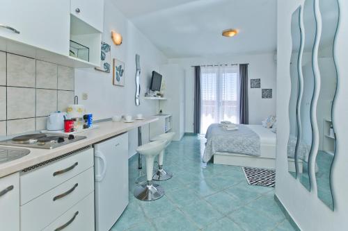 a kitchen with white cabinets and a bed in a room at Apartments Anita in Hvar