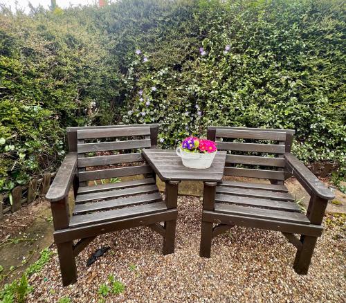 Prelude Guesthouse, Brigsley Grimsby في غريمسبي: طاولة وجلسة خشبتين مع وعاء من الزهور عليه