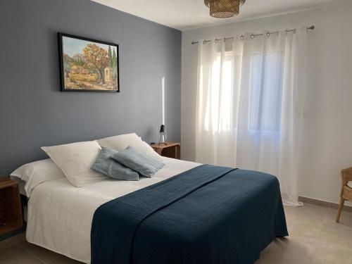 - une chambre avec un lit doté d'une couverture bleue et d'une fenêtre dans l'établissement Moun Cabanoun, à Carpentras