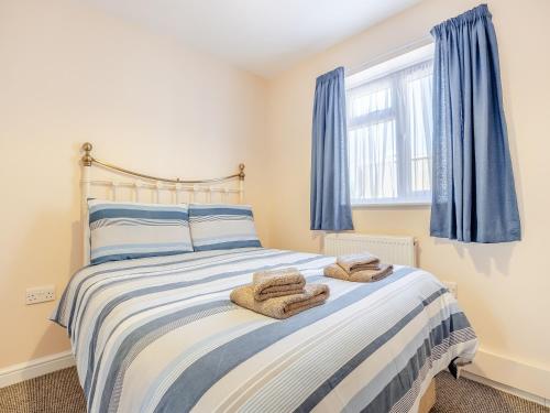 a bedroom with a bed with blue curtains at Maceys Cottage - Uk42146 in North Somercotes