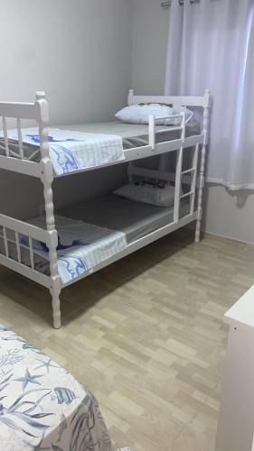 two bunk beds in a room with a wooden floor at Casa Praia&Ferias 300 metros Praia da Enseada in São Francisco do Sul