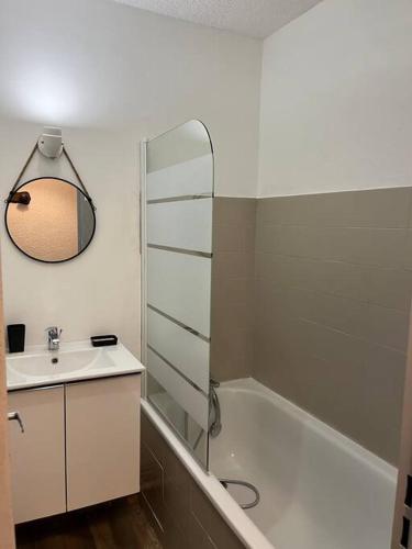 une salle de bain avec un lavabo, une baignoire et un miroir dans l'établissement Appartement moderne & chaleureux, à Gréoux-les-Bains