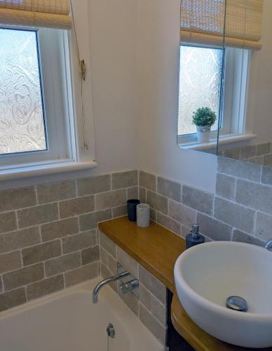 a bathroom with a sink and a tub and two windows at Spring Gardens, 4-bedroom seaside family home in Shanklin
