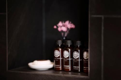 a shelf with three bottles of honey and a vase with flowers at Maison Proust, Hotel & Spa La Mer in Paris