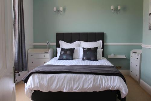a bedroom with a black and white bed with pillows at Spring Gardens, 4-bedroom seaside family home in Shanklin