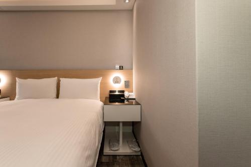 a hotel room with a bed and a night stand at HUB HOTEL Tucheng in Tucheng