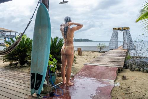 un homme debout sur un quai à côté d'une planche de surf dans l'établissement Casa del Fuego - Caribbean Beachfront Magic!, à Bocas del Toro