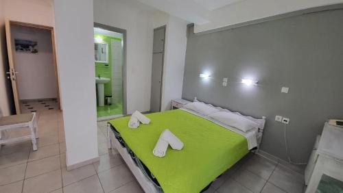 sypialnia z zielonym łóżkiem z butami w obiekcie Atlas Pension w mieście Karterados