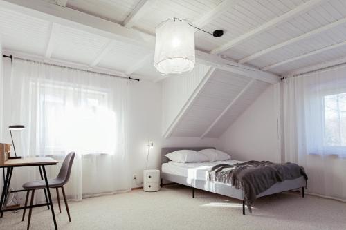 a white bedroom with a bed and a desk and window at Tuyo Casa Sarabandy in Warsaw