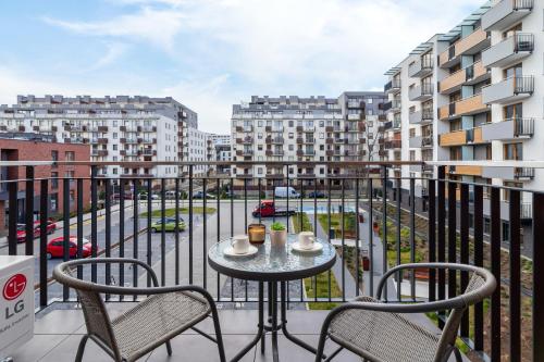 einen Tisch und Stühle auf einem Balkon mit Gebäuden in der Unterkunft Lux Apartment Grzegórzecka Estate Cracow by Renters Prestige in Krakau