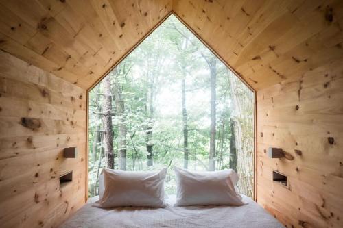 a bedroom in a tree house with a large window at Gather Greene in Coxsackie